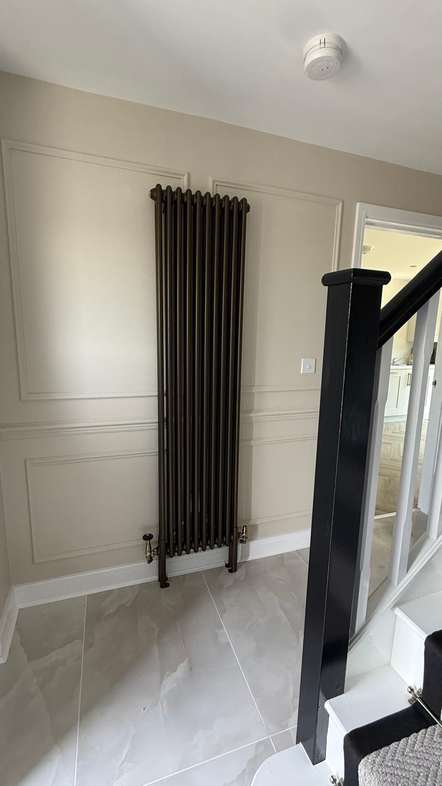 Finished antique gold vertical radiator fitted by the staircase in Bloxwich home