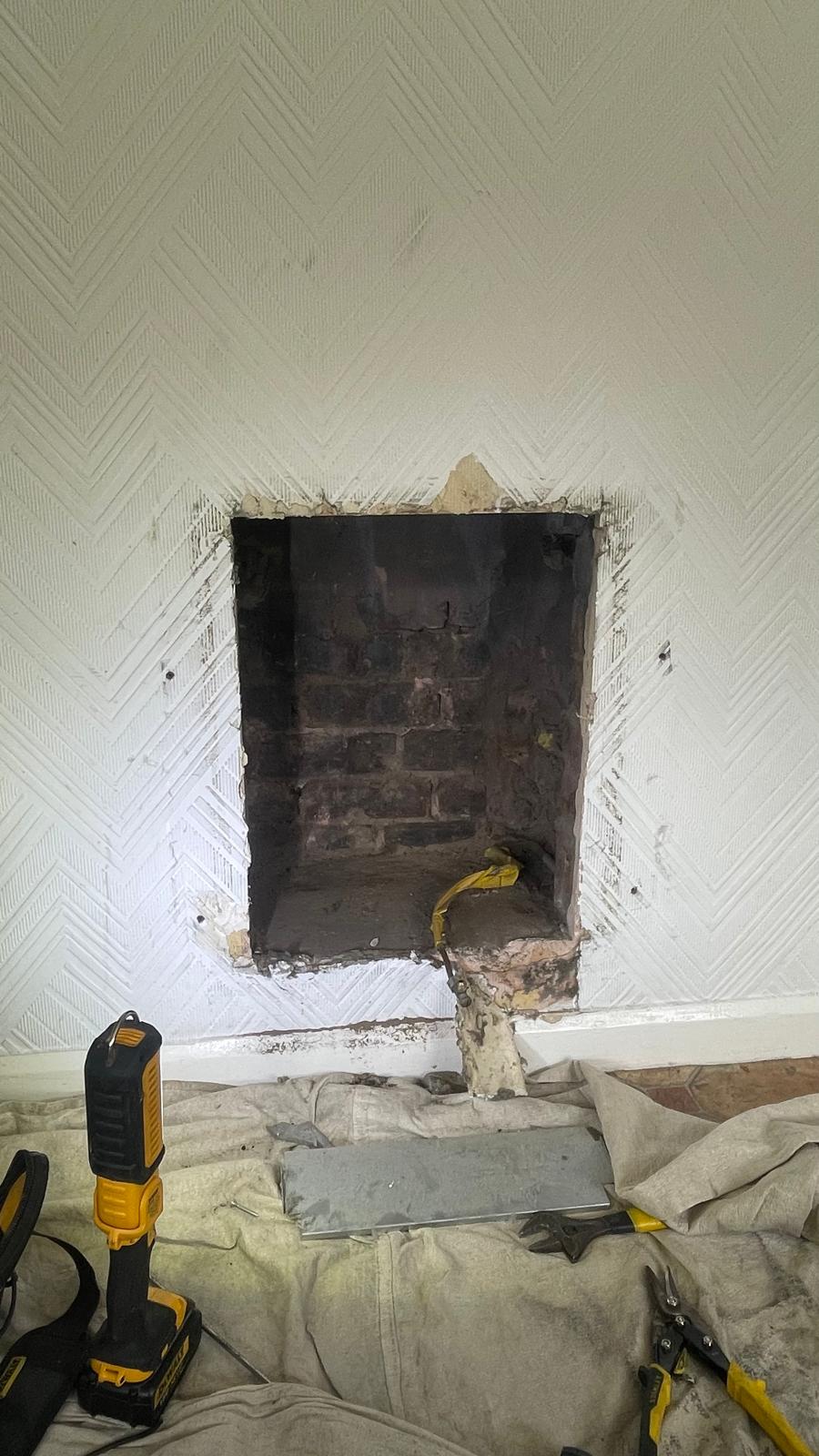 Empty fireplace opening after old gas fire removed with tools on dust sheet