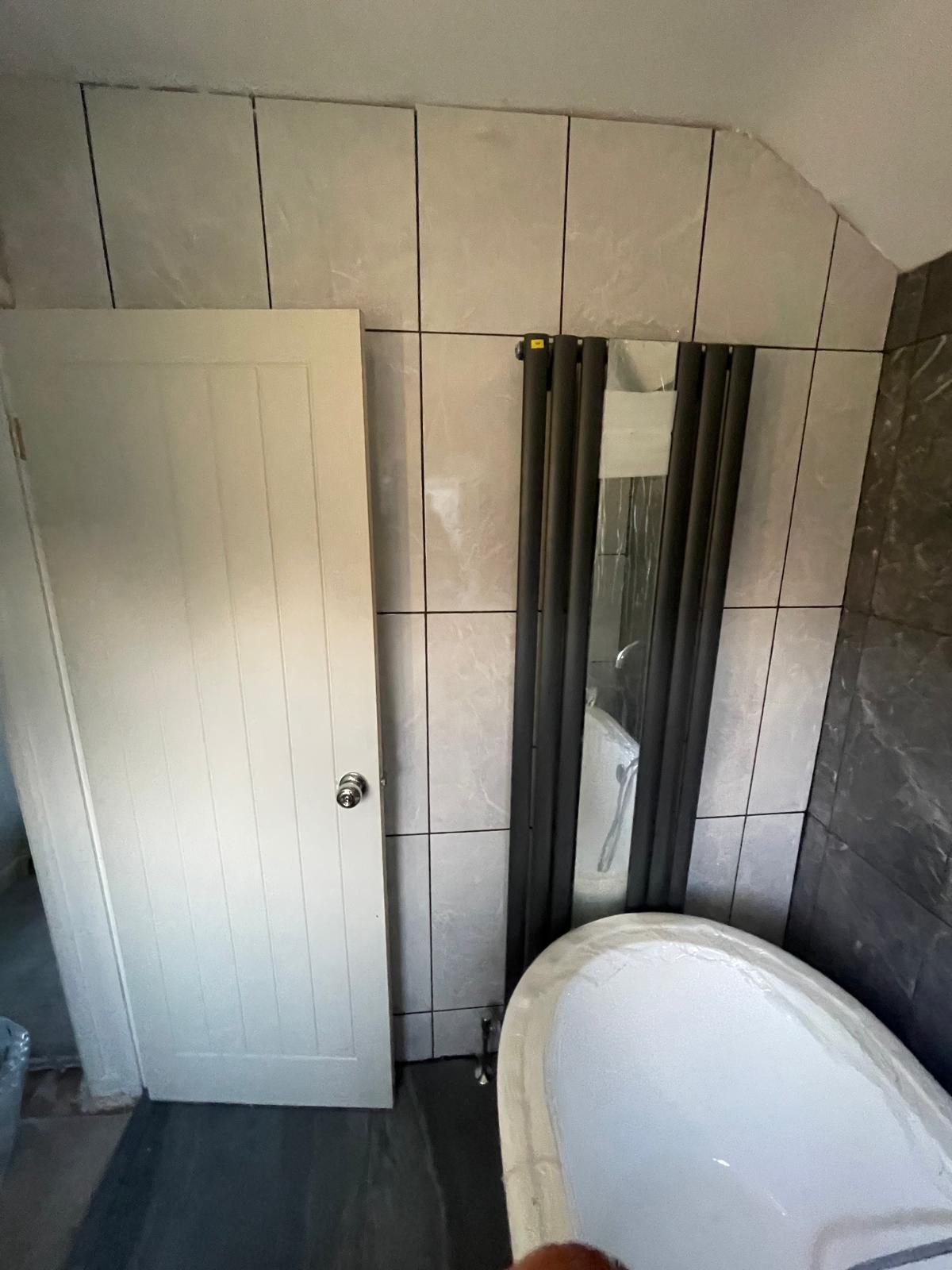 Full bathroom view showing freestanding bath, vertical radiator and new door in Wednesbury