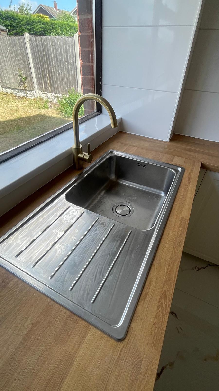 Stainless steel sink with brass tap set in oak worktop by window in Park Hall, Walsall kitchen