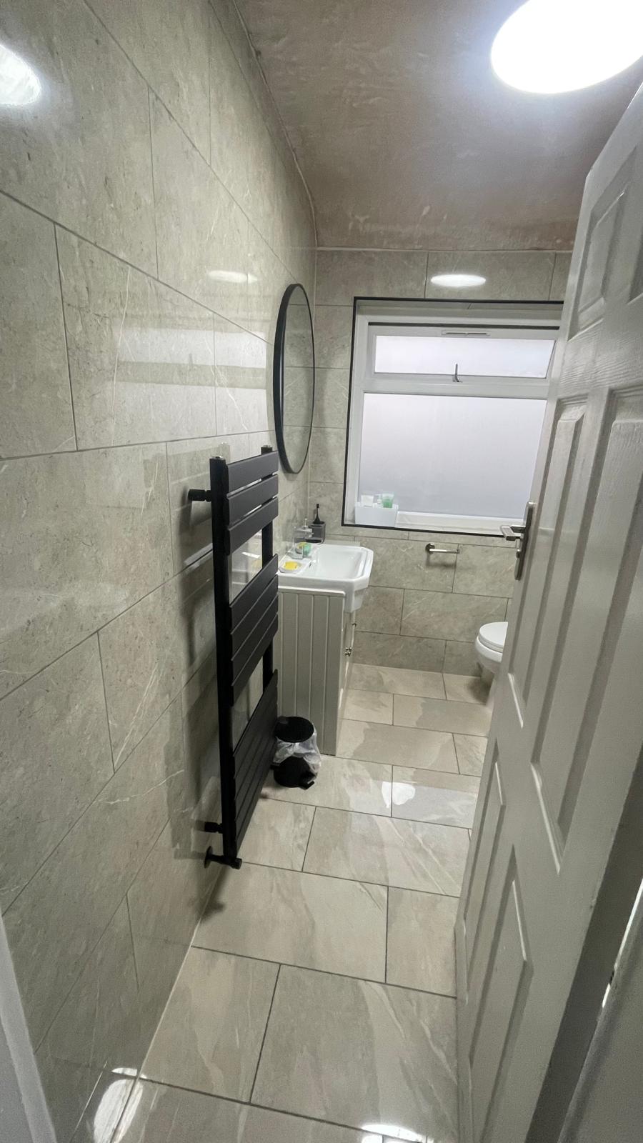 Dark grey towel radiator installed in a modern tiled bathroom in Wednesbury