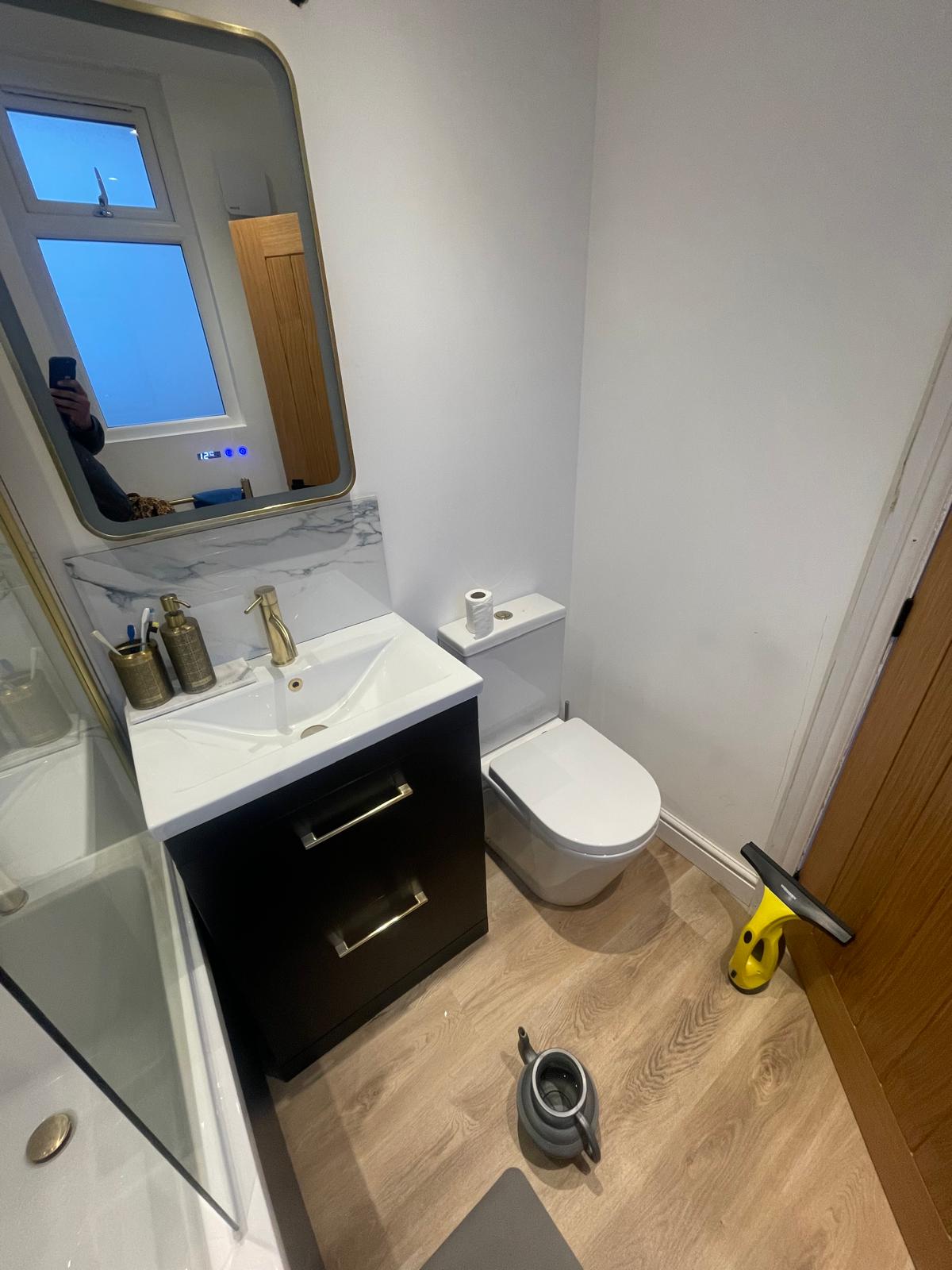 Completed bathroom with gold fixtures and oak effect flooring