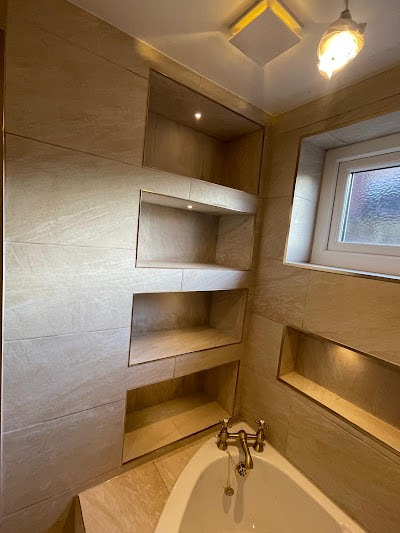 Gold rain shower head and handheld shower on herringbone tiled wall